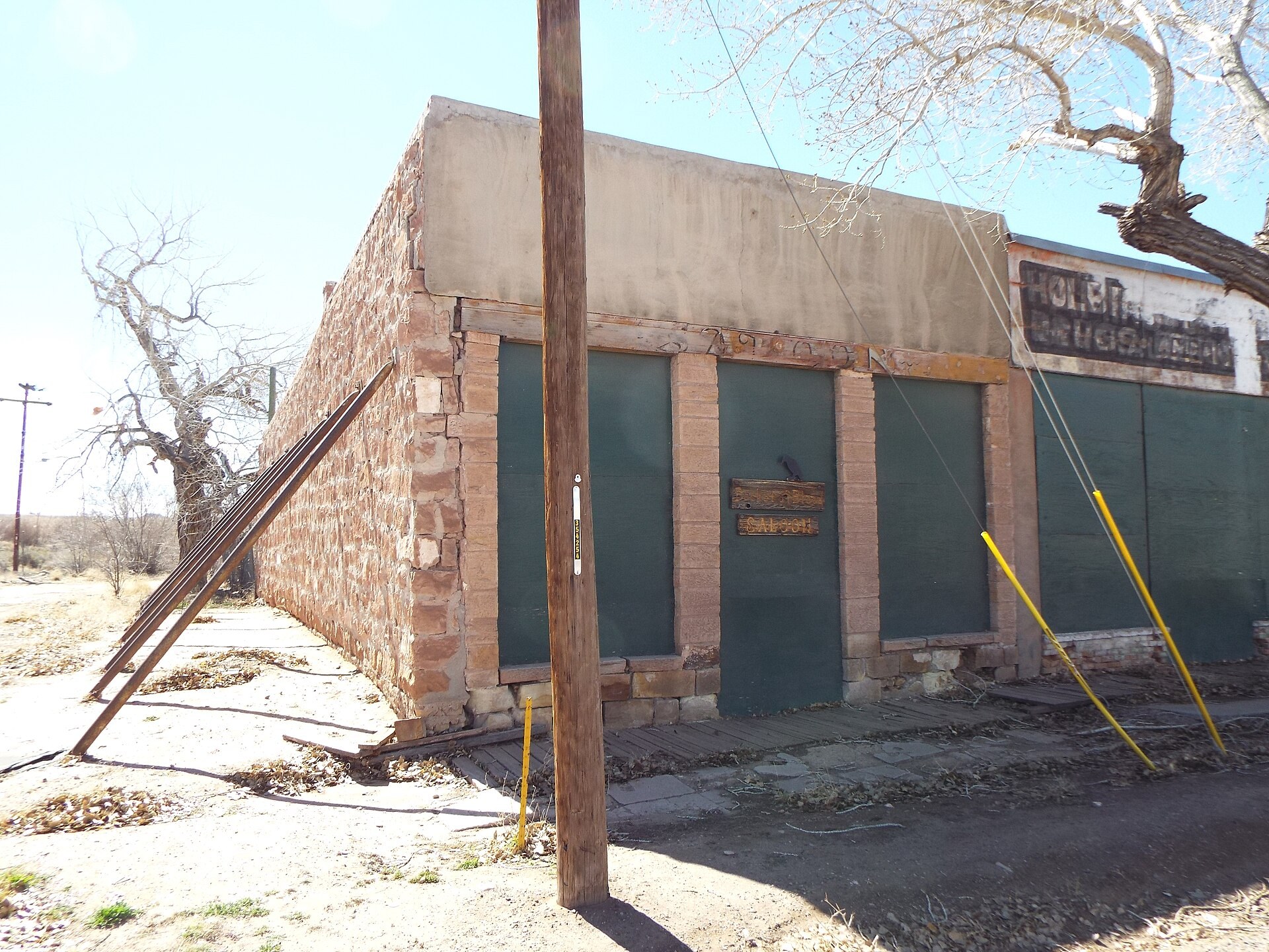 The sandstone front of the Bucket of Blood Saloon in Holbrook, Arizona, with green boarded windows and a wooden sign