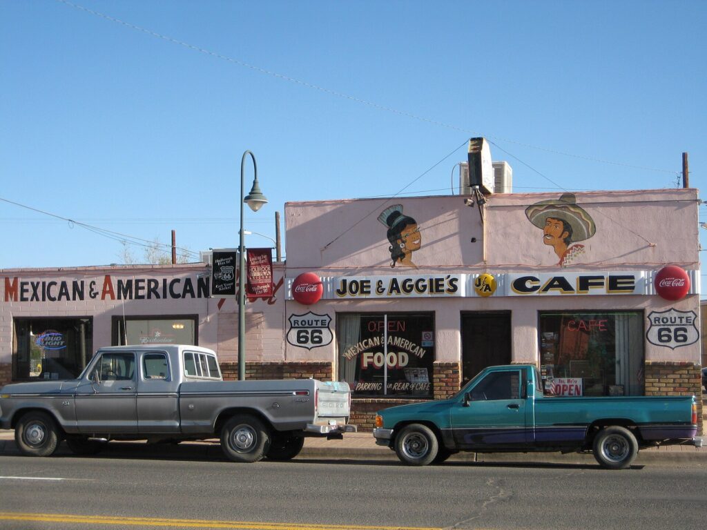 Joe and Aggie's Cafe on Route 66 in Holbrook in 2008, with its Mexican and American food sign, painted Route 66 shields and two old pickup trucks parked out front